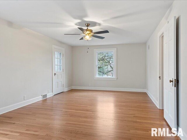 empty room featuring baseboards, a ceiling fan, and light wood-style floors