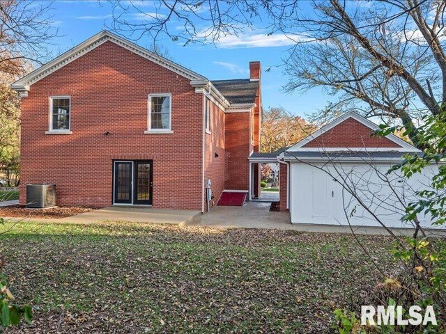 rear view of property with brick siding, a patio, and central AC