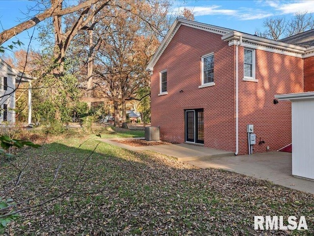 view of home's exterior with a patio, central AC, and brick siding