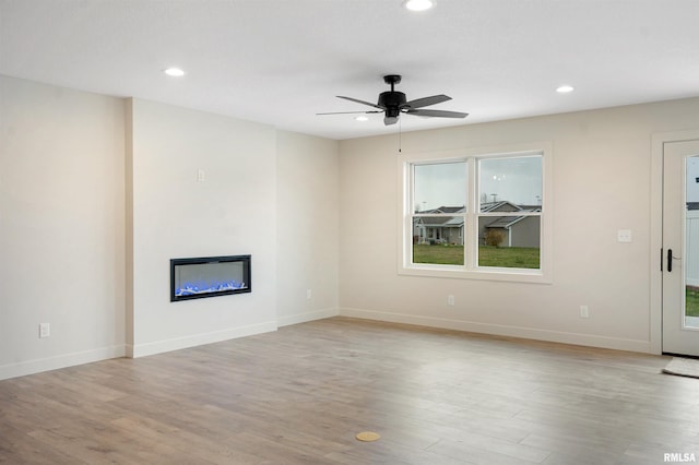 unfurnished living room with ceiling fan, a wealth of natural light, and light hardwood / wood-style flooring