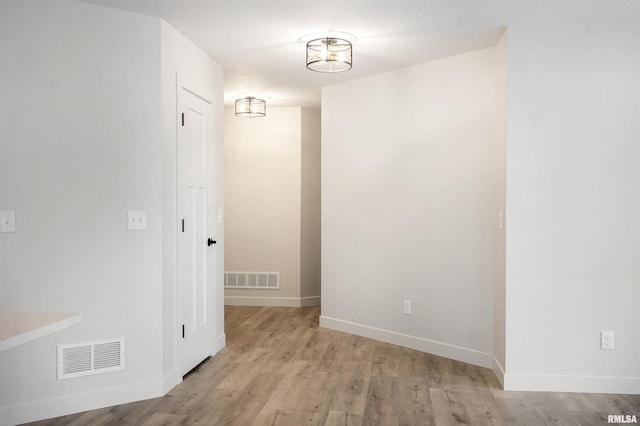 unfurnished room featuring baseboards, light wood finished floors, and visible vents