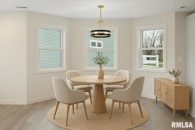 dining room with baseboards, visible vents, light wood-type flooring, and a notable chandelier