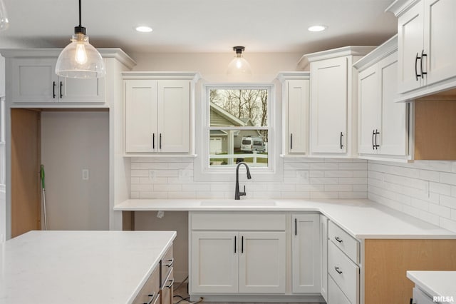 kitchen featuring backsplash, decorative light fixtures, white cabinetry, and sink