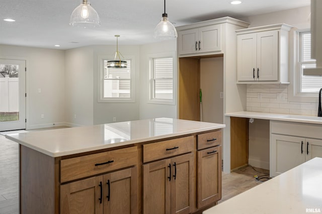 kitchen featuring sink, a kitchen island, light hardwood / wood-style floors, decorative light fixtures, and white cabinets