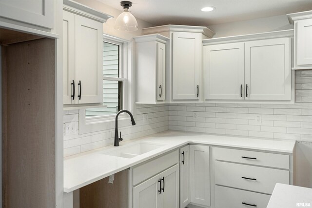 kitchen featuring a sink, light countertops, decorative backsplash, and white cabinets