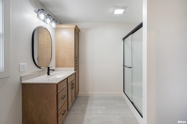 bathroom with vanity, baseboards, an enclosed shower, and wood finished floors