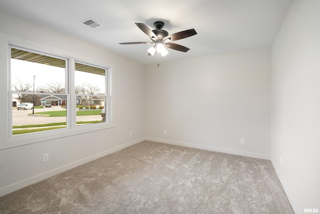 spare room with baseboards, visible vents, ceiling fan, and light colored carpet