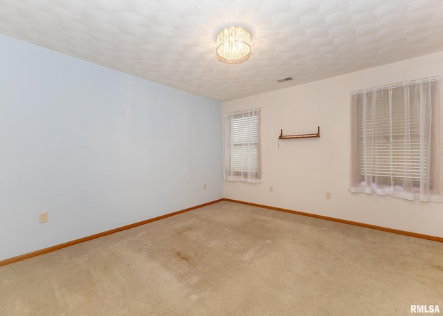 carpeted empty room with an inviting chandelier