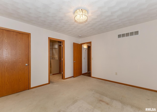 unfurnished bedroom featuring a notable chandelier, light carpet, and a closet