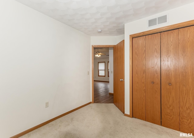 unfurnished bedroom featuring light colored carpet and a closet