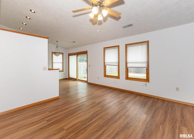 empty room featuring a textured ceiling, hardwood / wood-style flooring, and vaulted ceiling