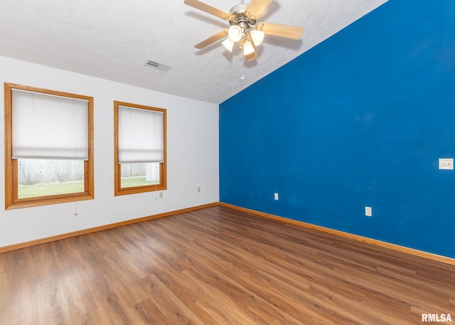 spare room with a textured ceiling, ceiling fan, wood-type flooring, and lofted ceiling