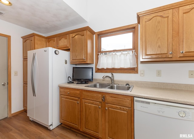 kitchen with light hardwood / wood-style floors, white appliances, and sink