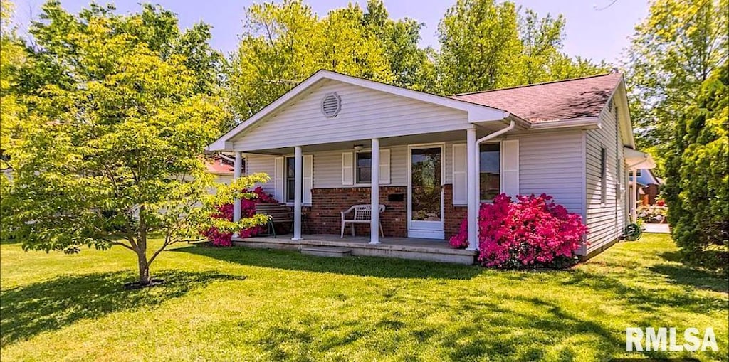 view of front of property featuring a front yard, brick siding, and covered porch