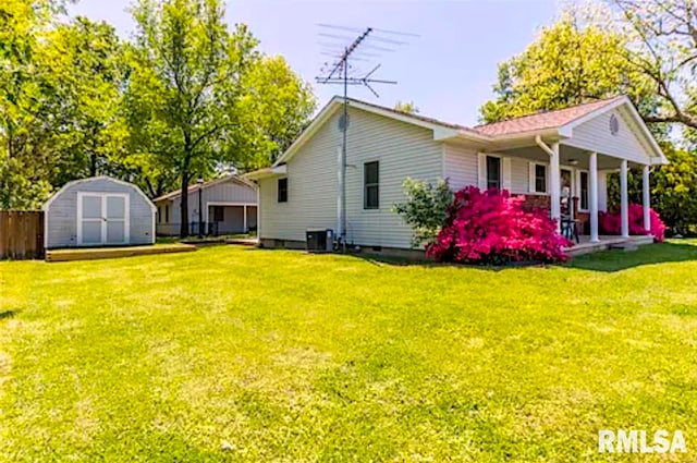 rear view of house featuring a porch, a shed, a yard, and central AC