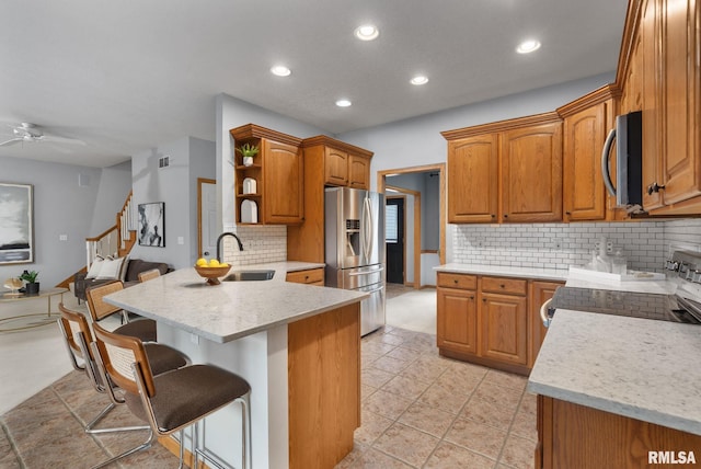 kitchen with ceiling fan, tasteful backsplash, kitchen peninsula, sink, and stainless steel appliances