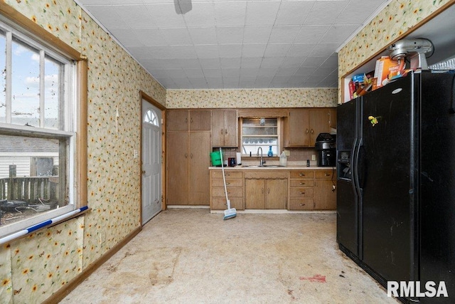 kitchen featuring light carpet, black fridge, and sink