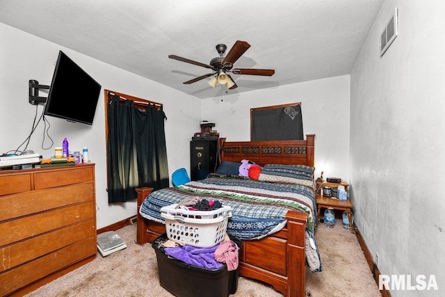 carpeted bedroom with ceiling fan and a textured ceiling