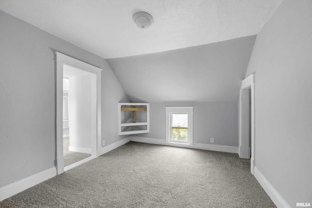 additional living space with carpet flooring, a textured ceiling, and vaulted ceiling