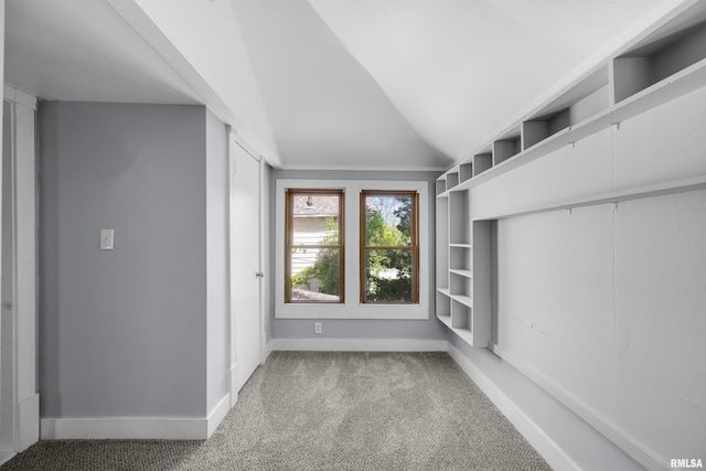 carpeted empty room with vaulted ceiling