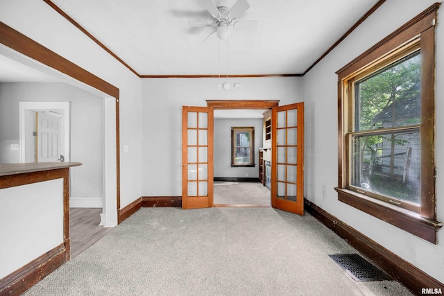 empty room featuring light carpet, french doors, and ornamental molding