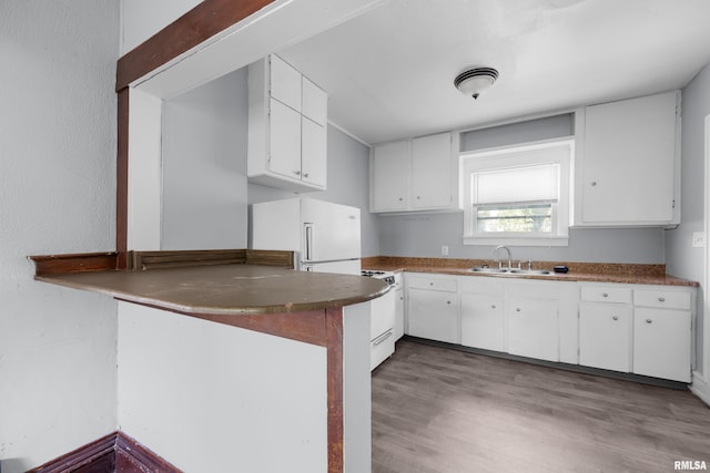 kitchen with hardwood / wood-style floors, white appliances, white cabinets, sink, and kitchen peninsula