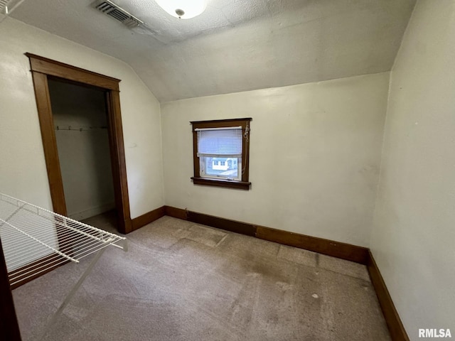 unfurnished bedroom featuring carpet flooring, a textured ceiling, a closet, and lofted ceiling