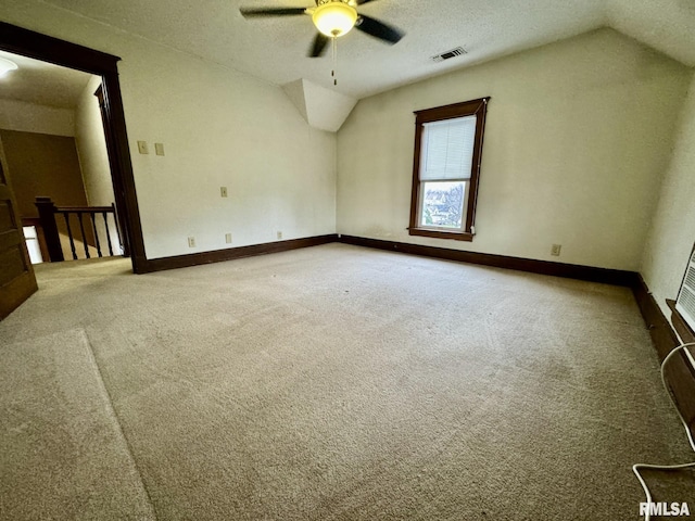 carpeted spare room with a textured ceiling, ceiling fan, and lofted ceiling