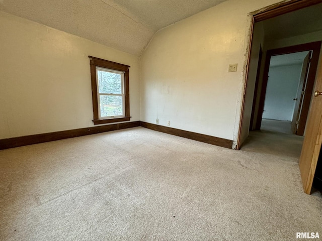 spare room with a textured ceiling, light carpet, and vaulted ceiling