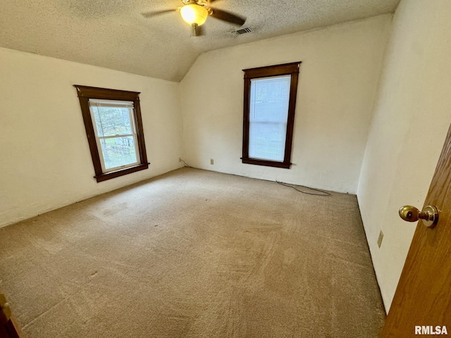 carpeted empty room featuring a textured ceiling, ceiling fan, and lofted ceiling