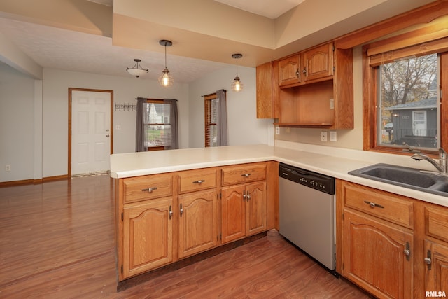 kitchen featuring a wealth of natural light, hanging light fixtures, stainless steel dishwasher, kitchen peninsula, and hardwood / wood-style floors