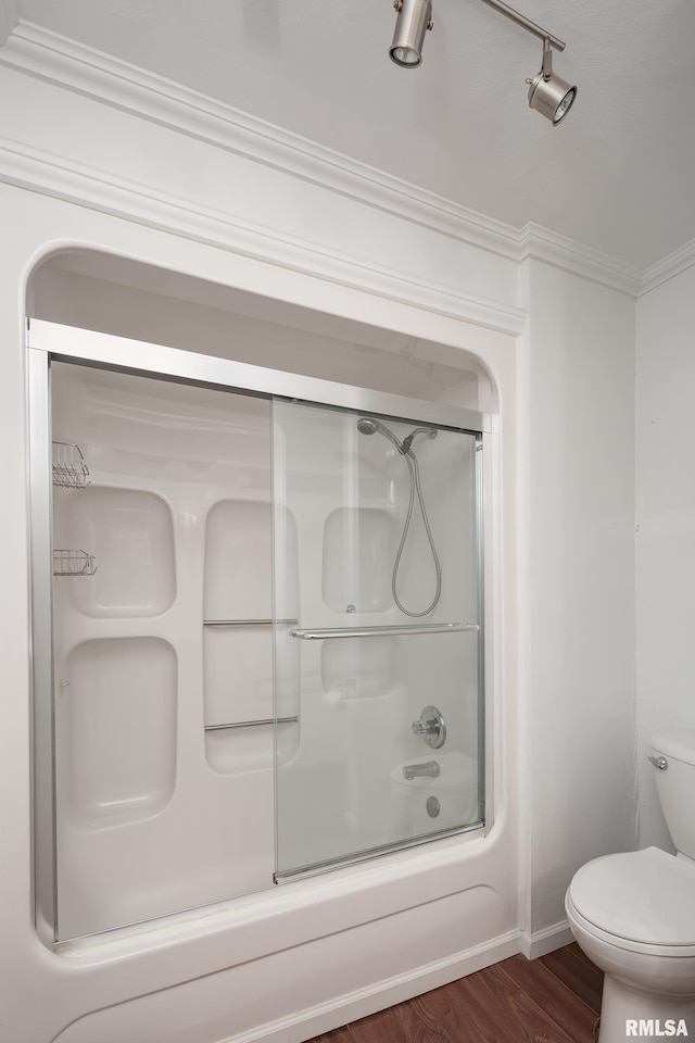 bathroom with crown molding, bath / shower combo with glass door, wood-type flooring, and toilet