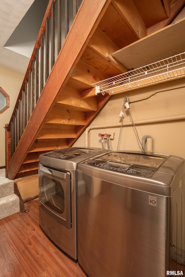 clothes washing area with washing machine and clothes dryer and hardwood / wood-style floors