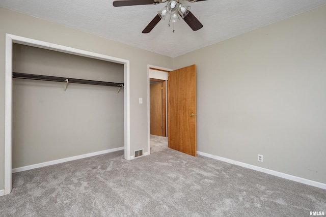 unfurnished bedroom with ceiling fan, light colored carpet, a textured ceiling, and a closet