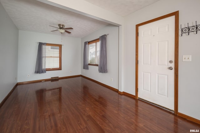 foyer entrance with a textured ceiling, dark hardwood / wood-style floors, and ceiling fan