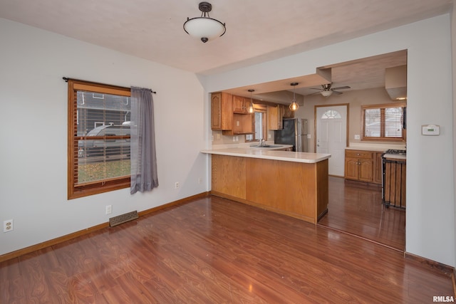 kitchen with sink, ceiling fan, dark hardwood / wood-style flooring, kitchen peninsula, and stainless steel refrigerator