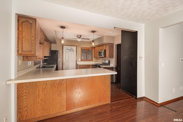 kitchen featuring sink, dark hardwood / wood-style floors, ceiling fan, appliances with stainless steel finishes, and kitchen peninsula