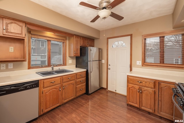 kitchen with appliances with stainless steel finishes, dark hardwood / wood-style floors, ceiling fan, and sink