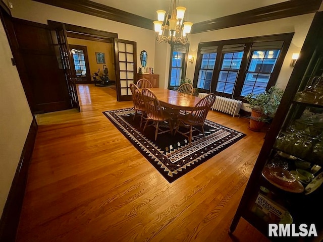 dining space featuring light hardwood / wood-style flooring, ornamental molding, plenty of natural light, and an inviting chandelier