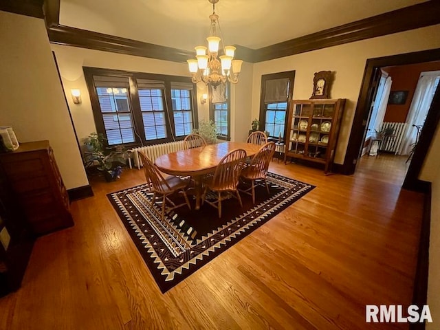 dining room with hardwood / wood-style floors, crown molding, and a notable chandelier