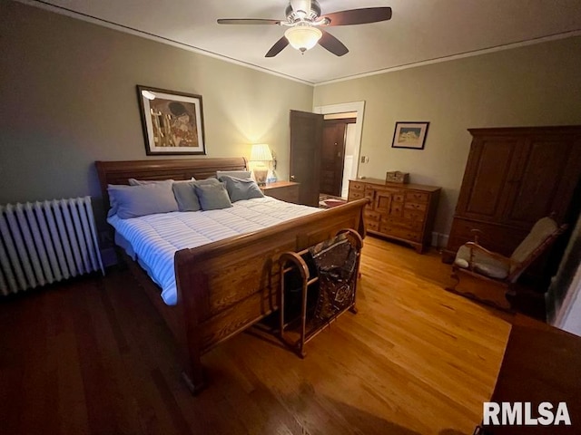 bedroom with hardwood / wood-style flooring, ceiling fan, ornamental molding, and radiator heating unit