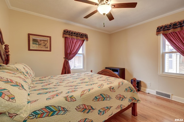 bedroom with multiple windows, crown molding, light wood-type flooring, and ceiling fan