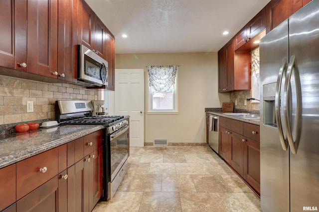 kitchen with tasteful backsplash, sink, dark stone counters, and appliances with stainless steel finishes