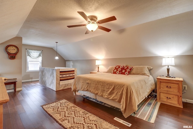 bedroom with ceiling fan, dark hardwood / wood-style flooring, vaulted ceiling, and a textured ceiling