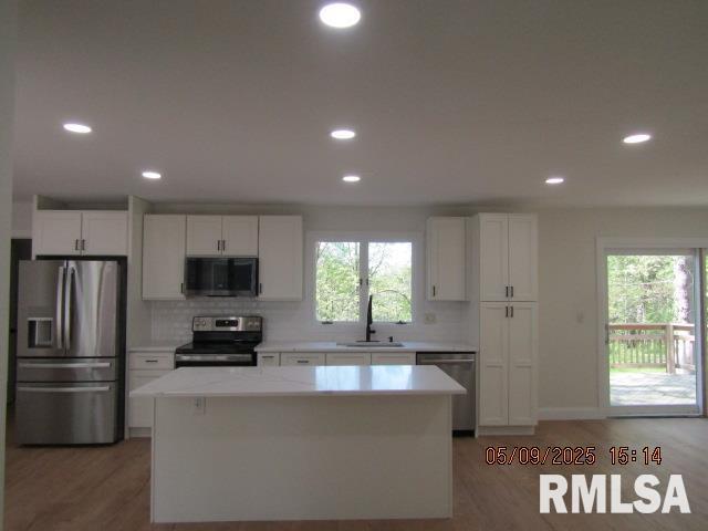 27339 Sherry Ann Ct, Donahue, IA 52746 - kitchen with appliances with stainless steel finishes, recessed lighting, a center island, white cabinets, and light countertops