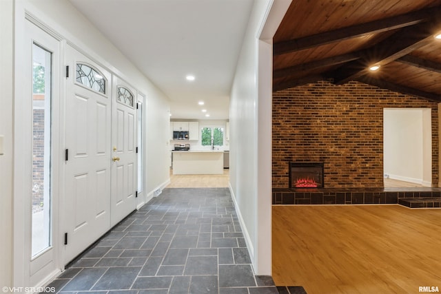 27339 Sherry Ann Ct, Donahue, IA 52746 - foyer featuring brick wall, a fireplace, wood ceiling, and recessed lighting