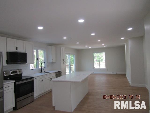 27339 Sherry Ann Ct, Donahue, IA 52746 - kitchen with stainless steel electric stove, a sink, a center island, white cabinetry, and recessed lighting