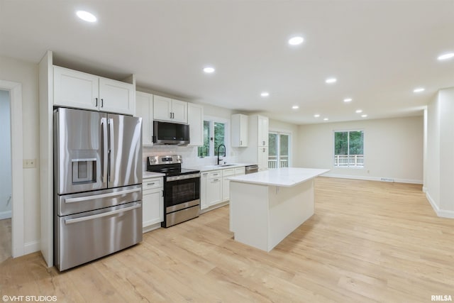 27339 Sherry Ann Ct, Donahue, IA 52746 - kitchen featuring appliances with stainless steel finishes, white cabinetry, light wood-style flooring, a center island, and recessed lighting