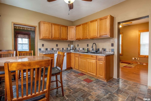 kitchen featuring light stone counters, ceiling fan, dark wood-type flooring, and sink