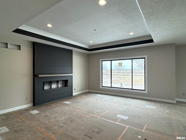 unfurnished living room featuring a fireplace, a raised ceiling, and a textured ceiling